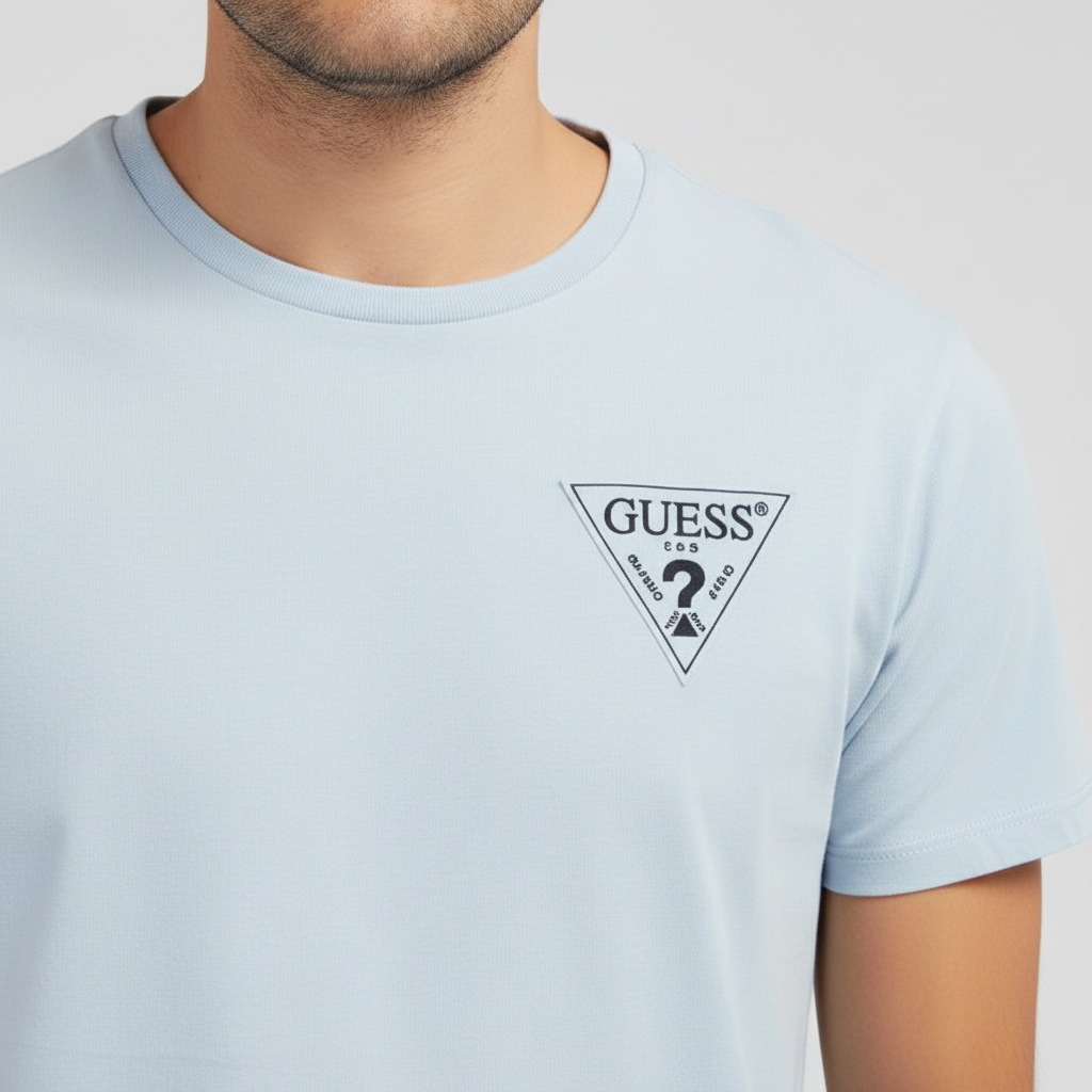 Close-up of textured triangle Guess logo on light blue T-shirt chest