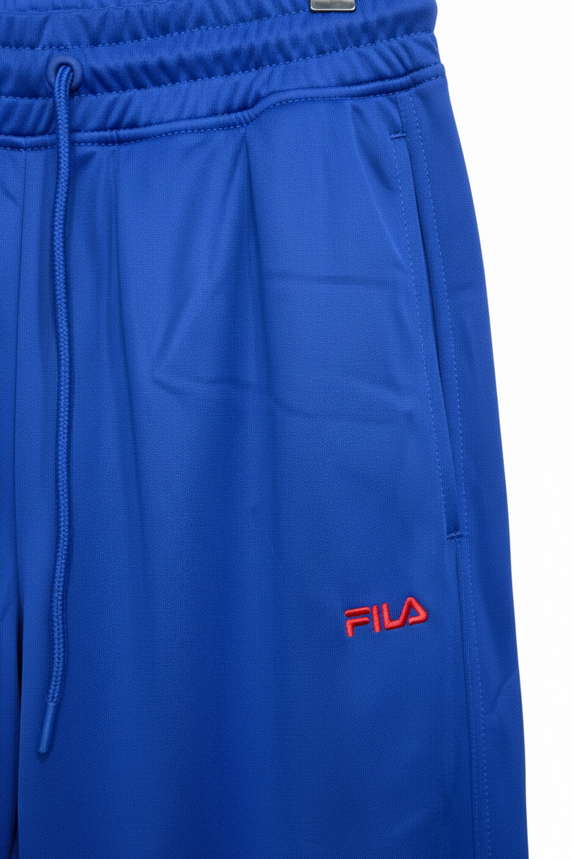 Close-up of red Fila logo on blue track pants