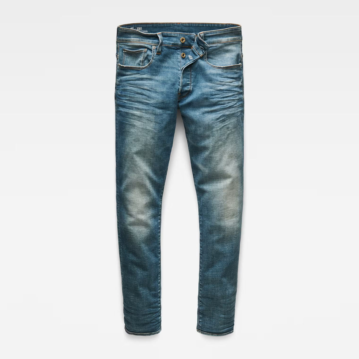 Front view of medium blue straight tapered jeans with distressed details on a white background
