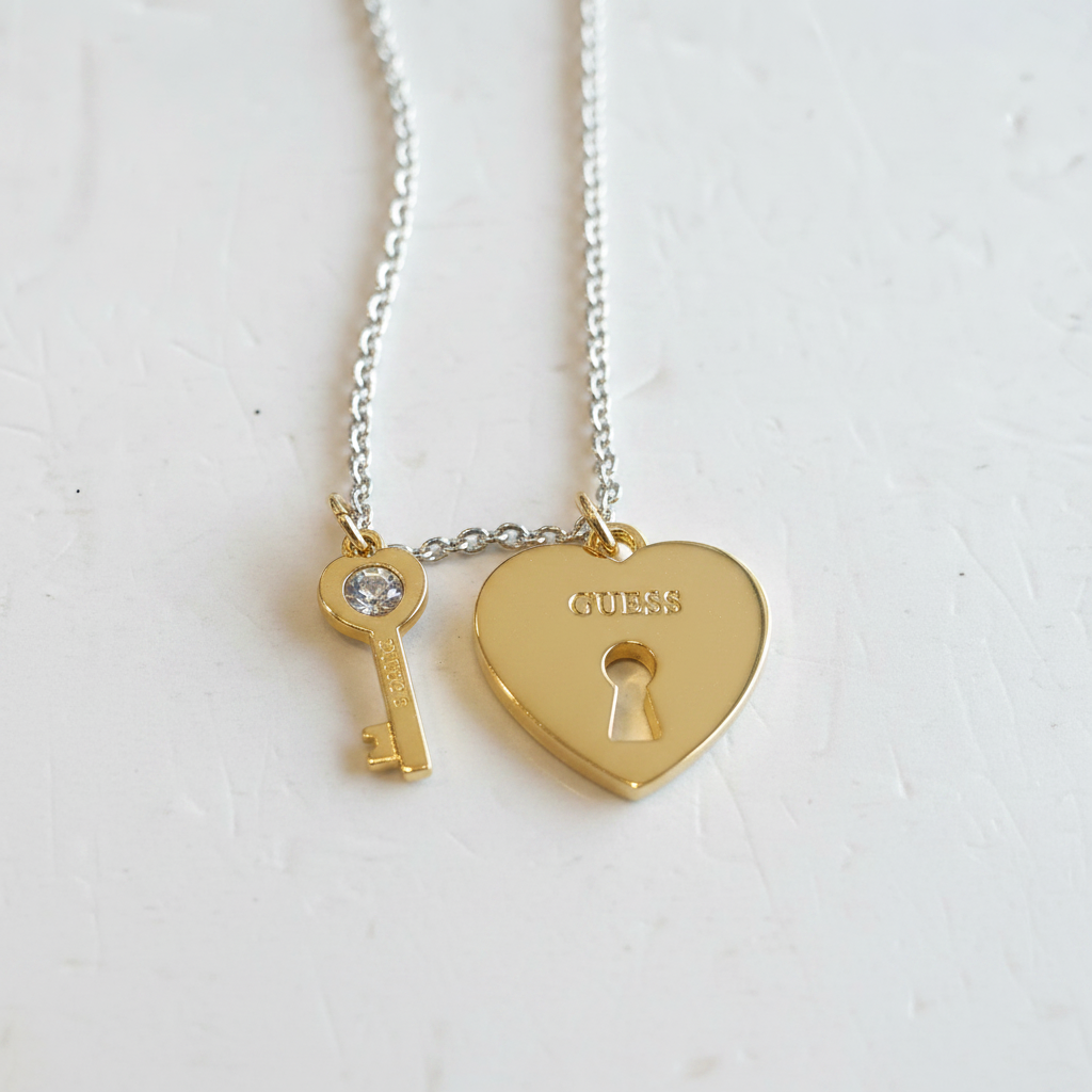 Close-up of gold heart lock and crystal key charms on Guess necklace
