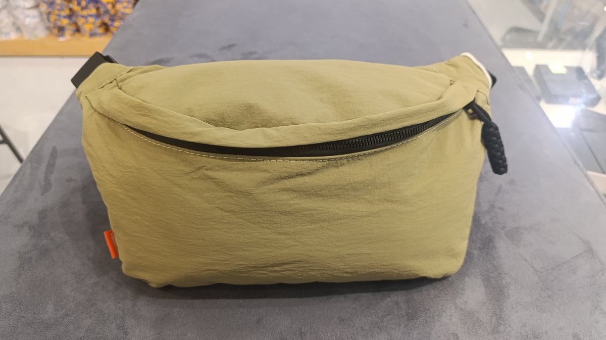 Back of olive canvas waist bag on shop counter