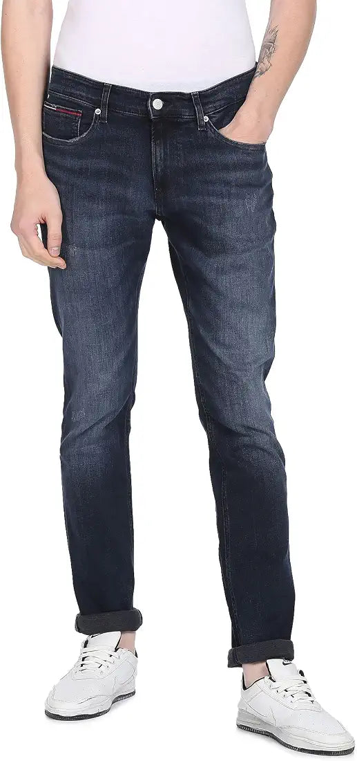 Tommy Jeans men's dark blue denim jeans with white sneakers, front view on model