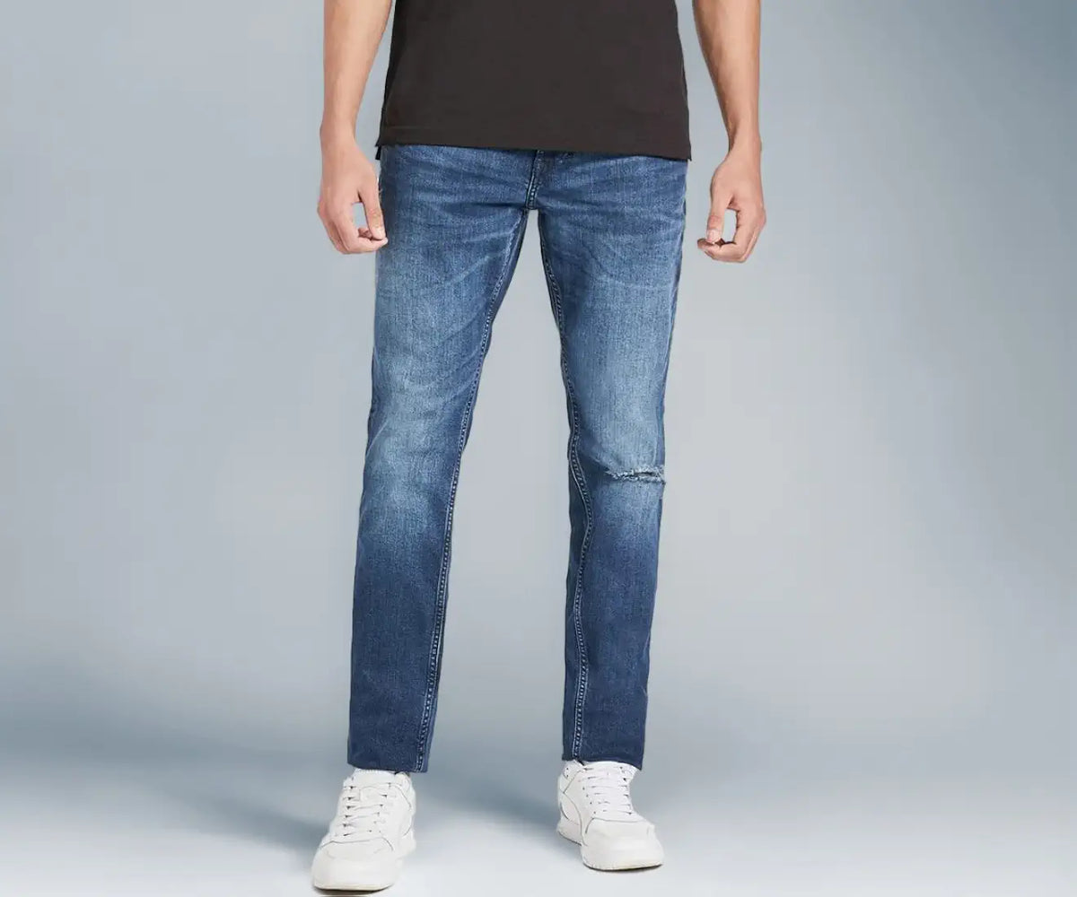 Tommy Hilfiger men's mid wash regular fit jeans with white sneakers, front view