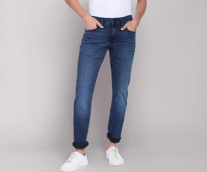Tommy Jeans men's faded blue denim jeans with white sneakers, front view on model