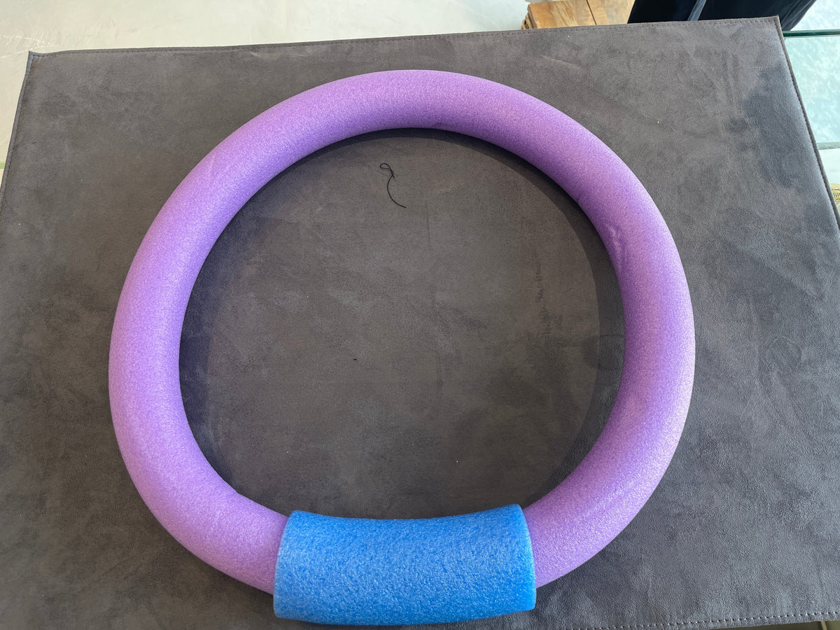 Purple foam pool noodle ring with blue connector on a table