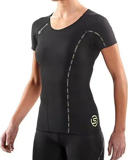 A woman athlete wearing a black SKINS Dnamic Women's Short Sleeve Top, performing a push-up exercise. Close-up of the SKINS Dnamic Women's Short Sleeve Top, highlighting the graduated compression zones and mesh panels. A group of diverse women athletes wearing SKINS Dnamic Women's Short Sleeve Tops in various colors, training together outdoors.