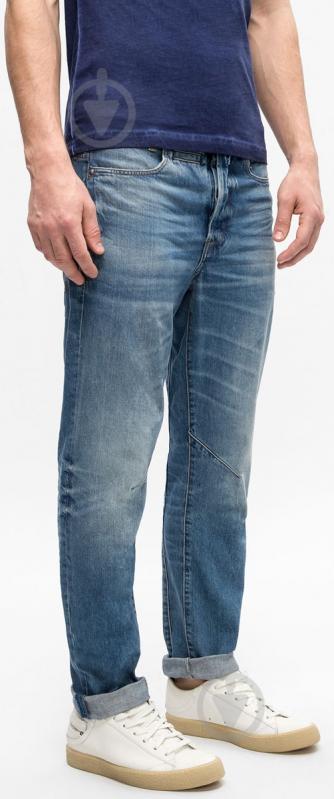 Side view of blue denim pants showcasing a faded design and slim fit against a white background.