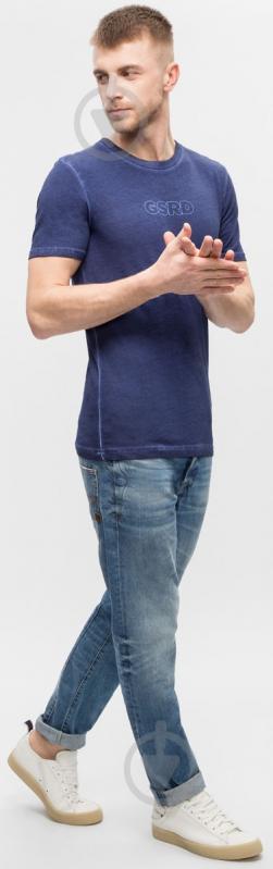 Lifestyle shot of blue denim pants featuring a faded design and slim fit on a white background.