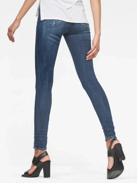 Side view of blue skinny jeans showcasing a fitted style and distressed details against a white background