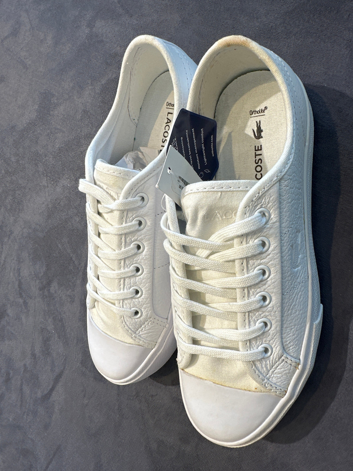 Lacoste white leather sneakers with tag, angled top view