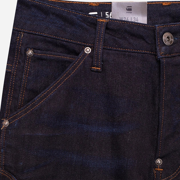 Close-up detail of dark blue jeans pocket showcasing stitching detail and metal button on a white background