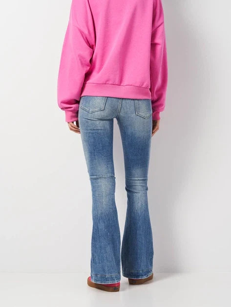Back view of flared jeans worn with a pink sweater, showcasing casual style on a white background.