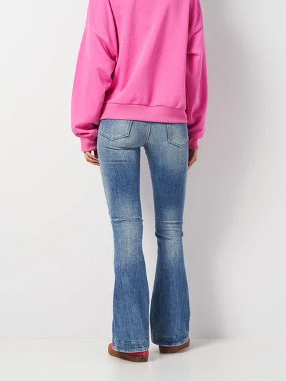 Back view of flared jeans worn with a pink sweater, showcasing casual style on a white background.