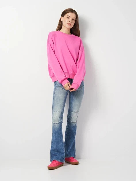 Lifestyle image featuring flared jeans and a pink sweater, highlighting casual style on a white background.
