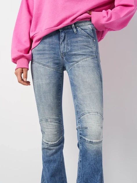 Detail close-up of blue flared jeans with a faded design on a white background.