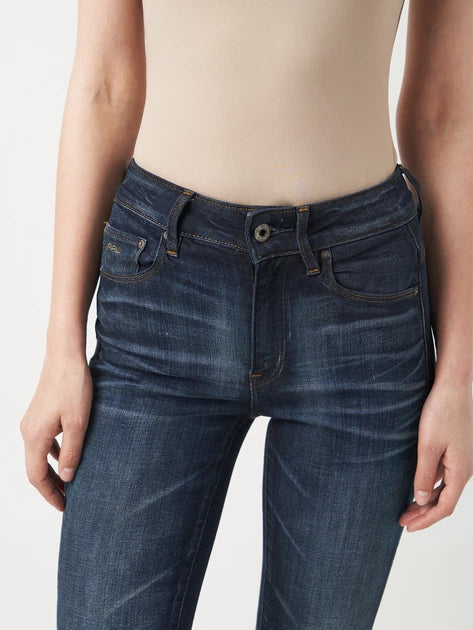 Detail close-up of the waistband featuring button closure and belt loops on dark blue jeans