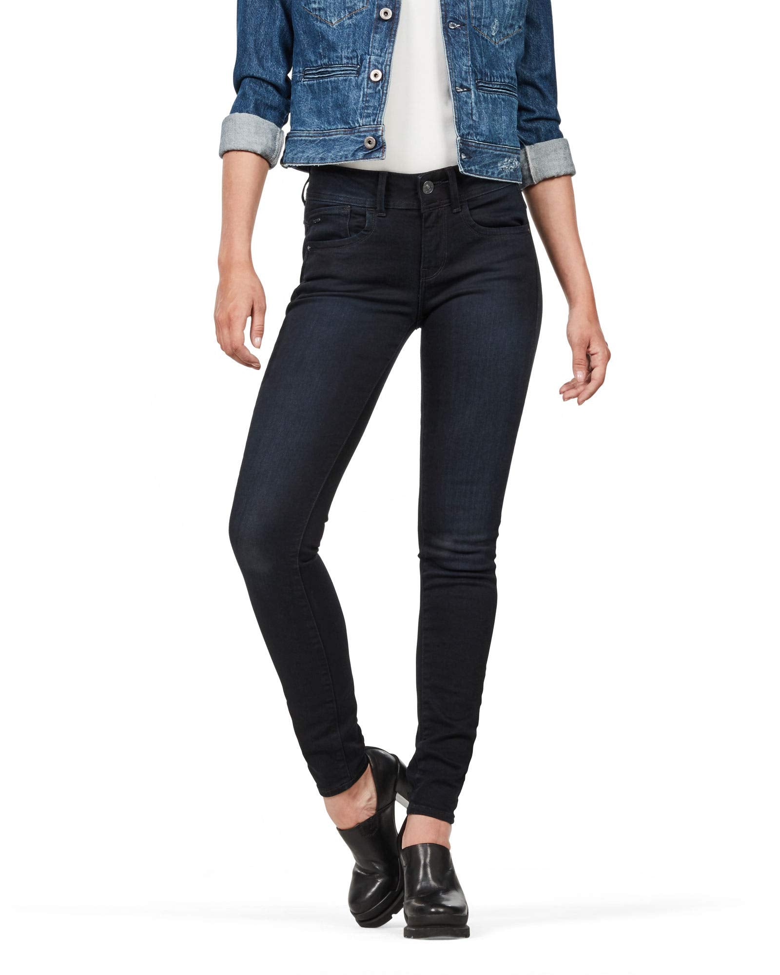 Lifestyle shot of dark jeans in a natural setting, emphasizing a skinny fit and high waist.