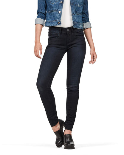 Lifestyle shot of dark jeans in a natural setting, emphasizing a skinny fit and high waist.