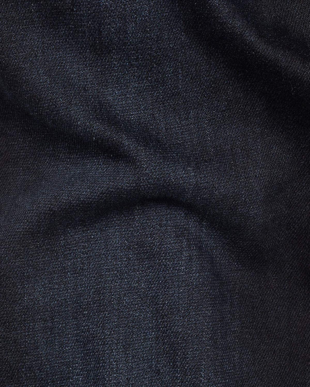Close-up detail of dark blue denim fabric highlighting its soft texture and stretch features.