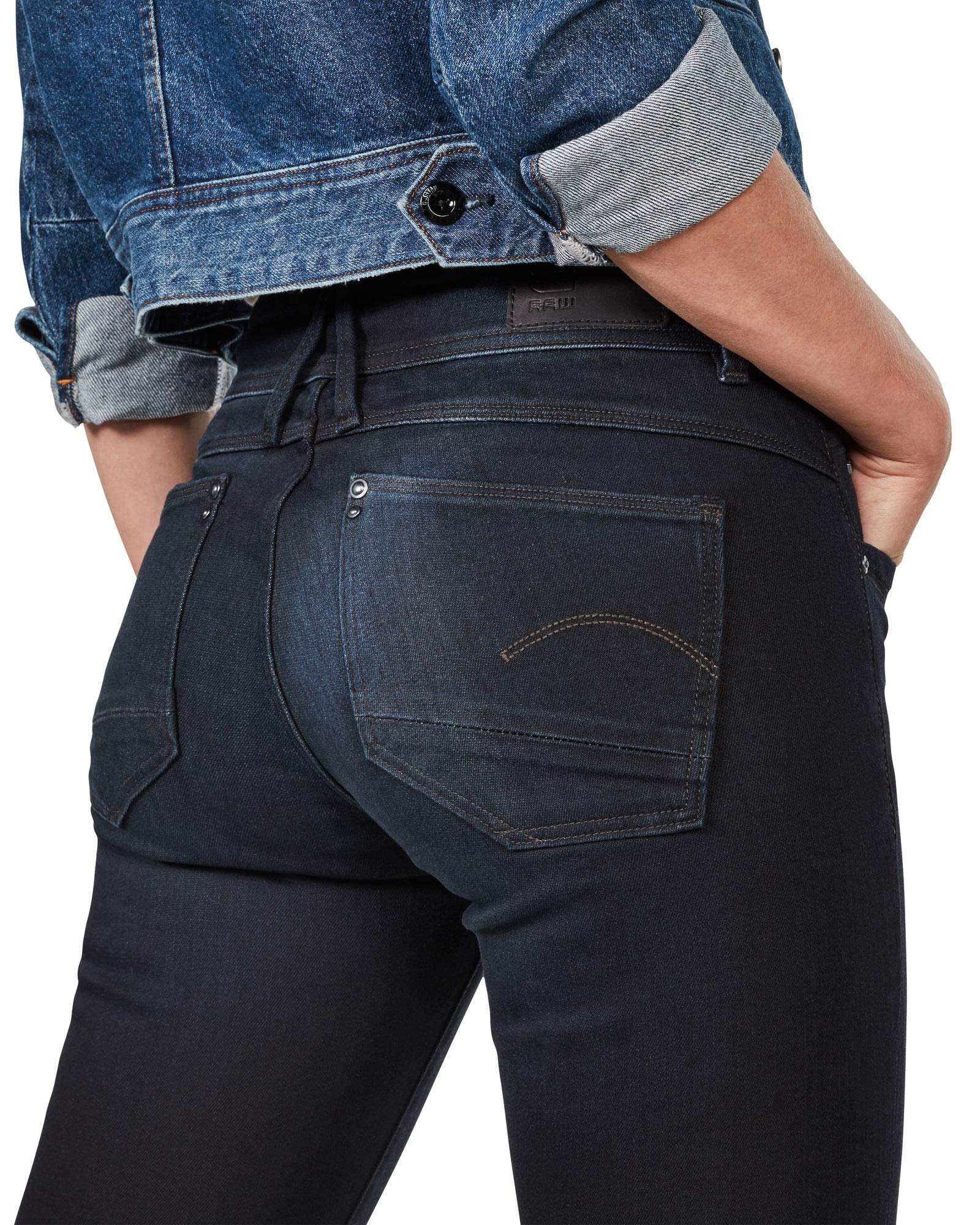 Back view of black skinny jeans showcasing back pockets and dark wash in a studio setting.