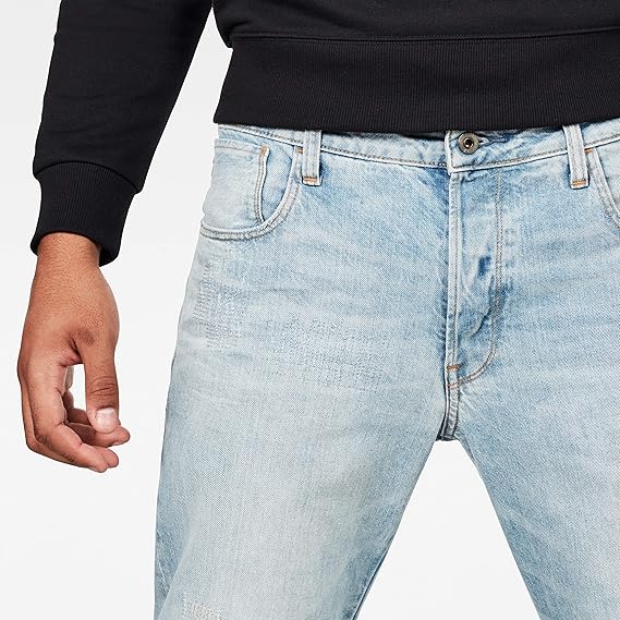 Detail close-up of light blue jeans featuring five pockets and a faded design against a white background.