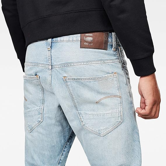 Back view highlighting the back pockets and brand label of light blue jeans on a white background.