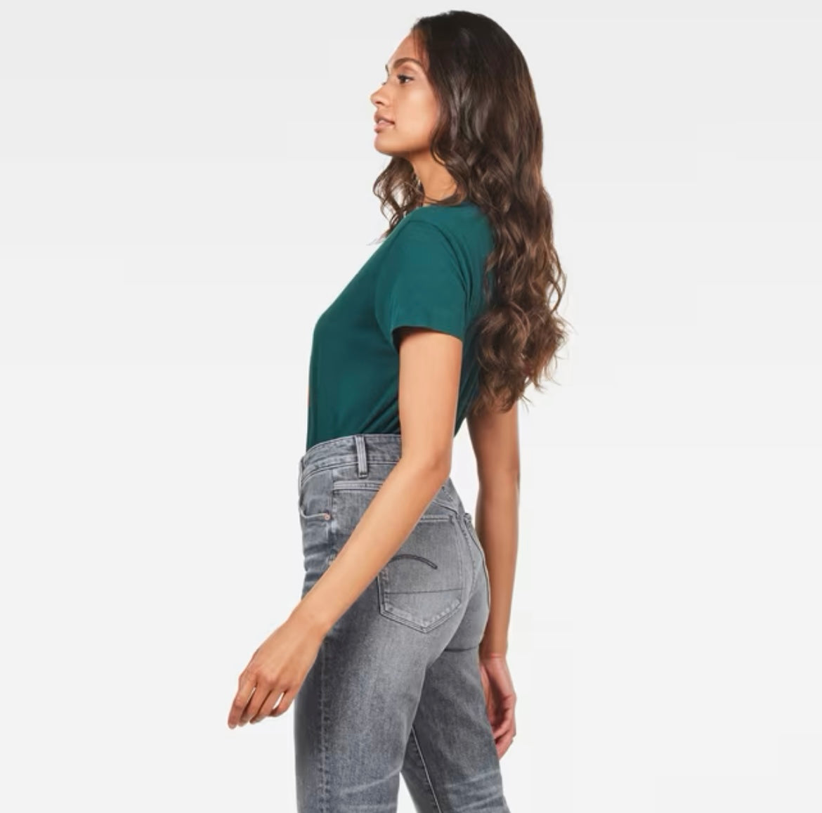 Side view of model in green G-Star Raw T-shirt tucked into grey jeans
