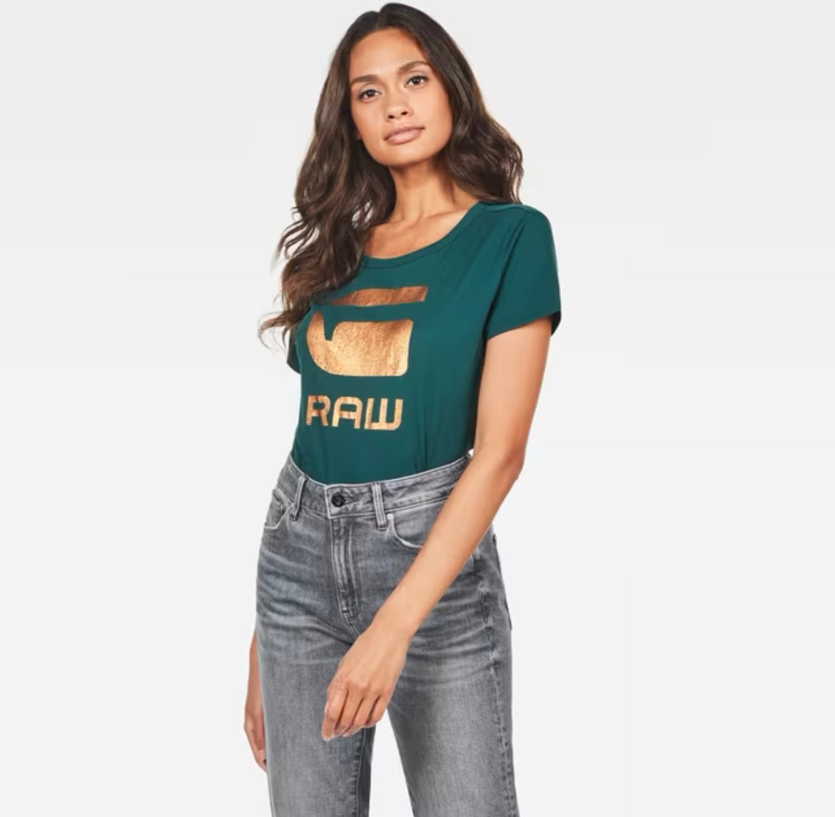Woman in pine green G-Star Raw T-shirt with gold G and RAW graphic, worn with grey jeans