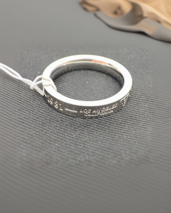 Silver Guess mix and mesh ring with tag on grey fabric