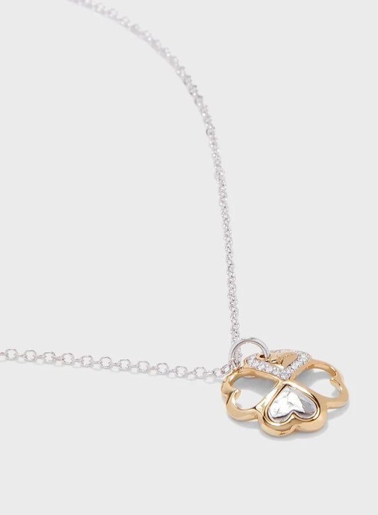 Close-up of Guess four heart clover leaf pendant in gold tone on silver chain