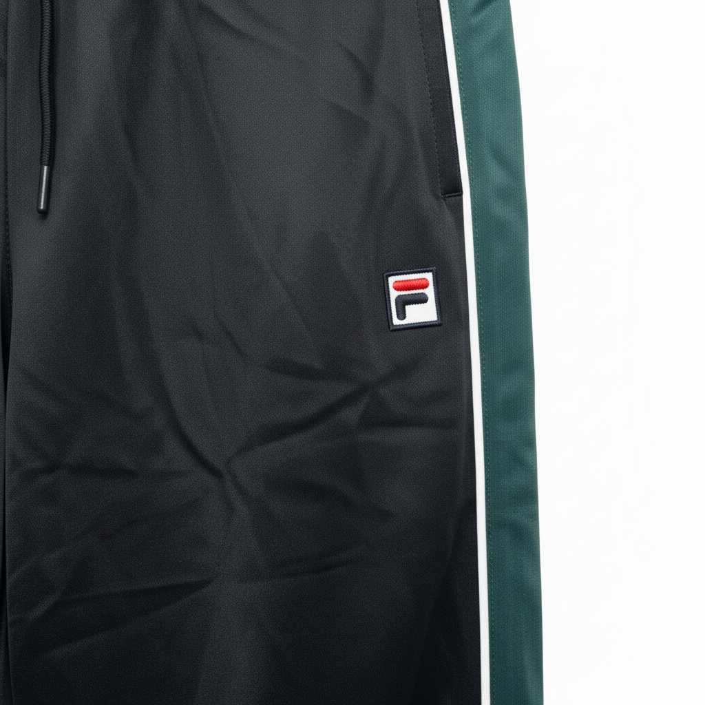 Close-up of Fila logo patch on black track pants