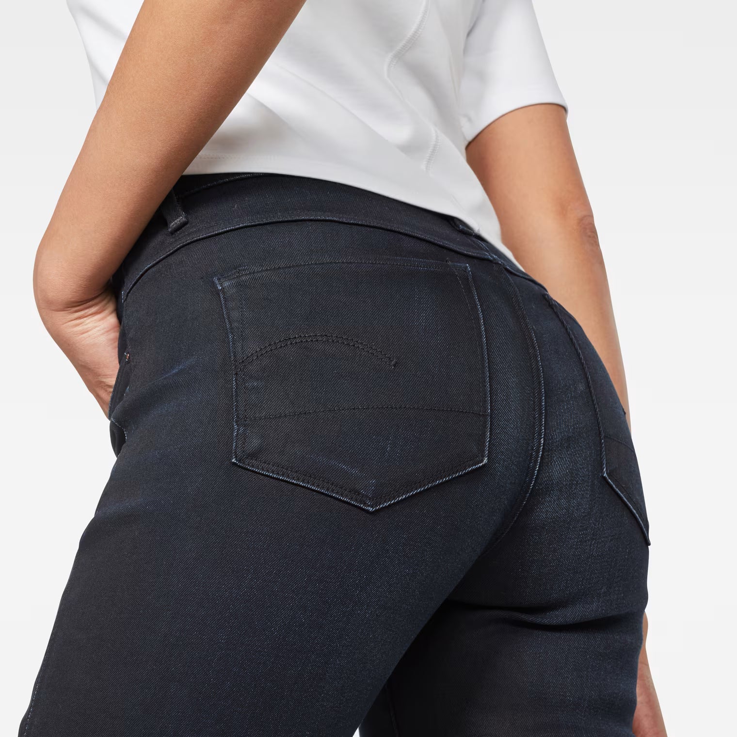 Close-up detail of dark blue skinny jeans showcasing back pocket and stitching.