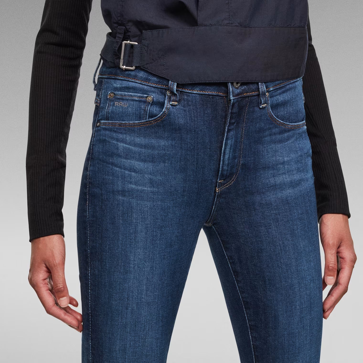 Detail close-up of medium blue skinny jeans with front pockets and zipper fly.