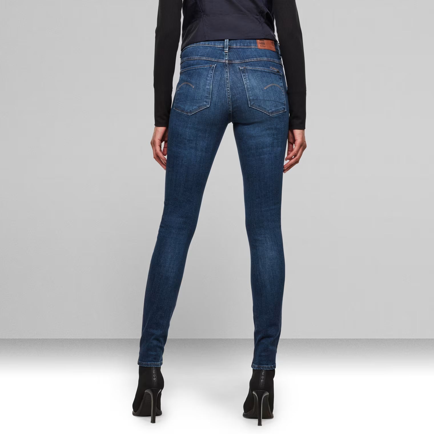 Back view of medium blue high waist skinny jeans highlighting the design.