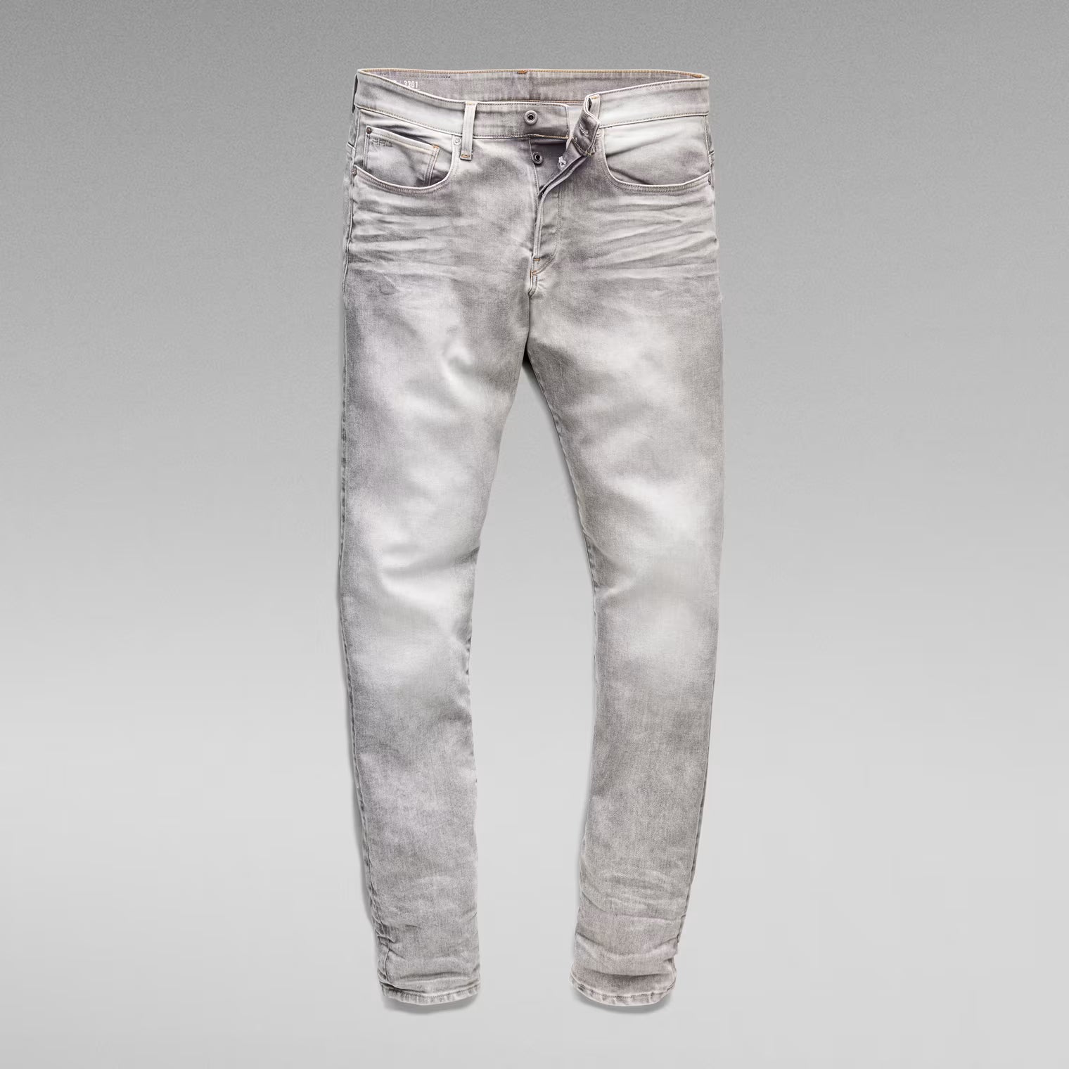 Unfolded front view of the grey tapered jeans on a solid background.
