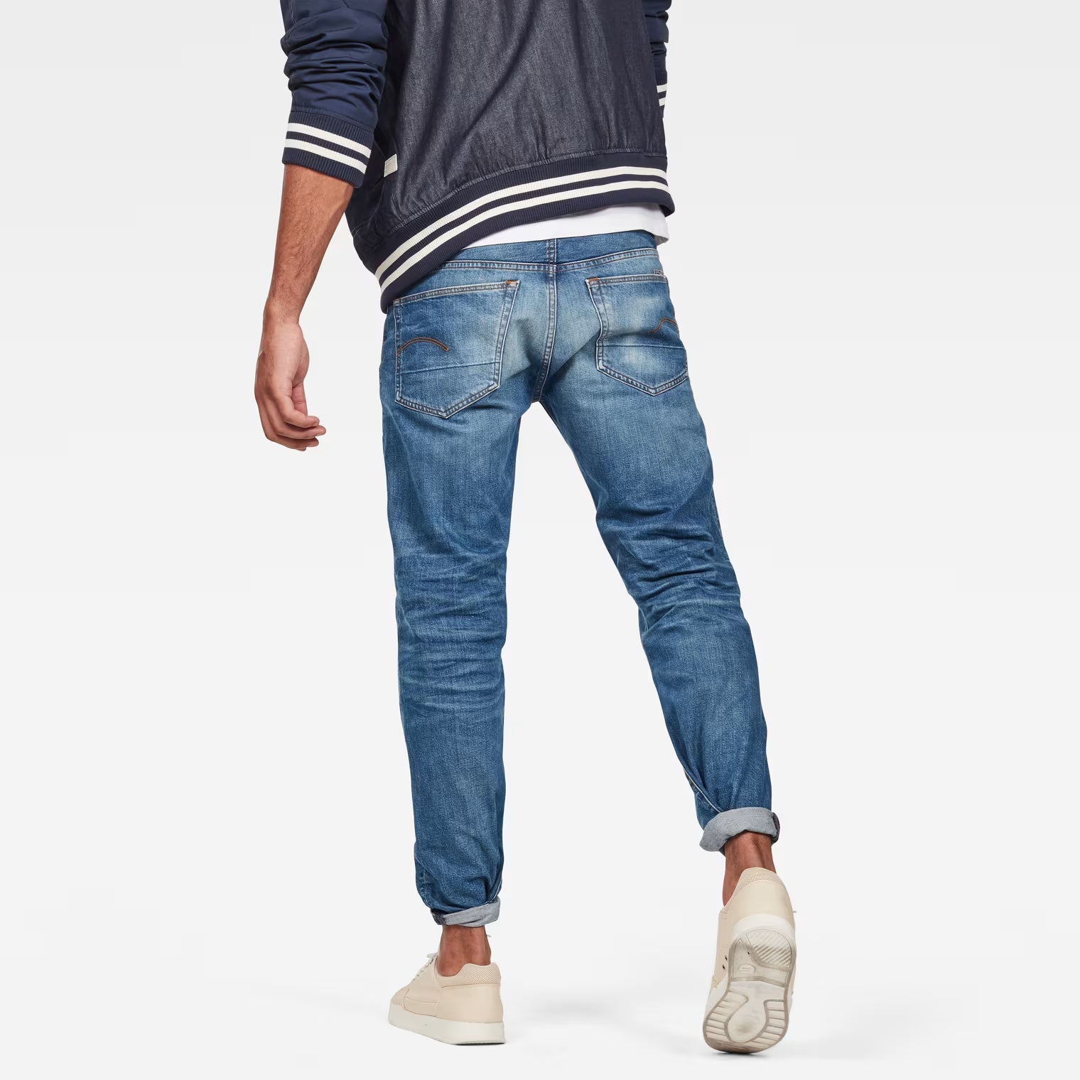 Back view of relaxed straight jeans in medium blue featuring distressed details and five pockets.