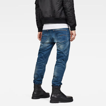 Back view of medium blue jeans showcasing a relaxed fit and distressed details on a white background.