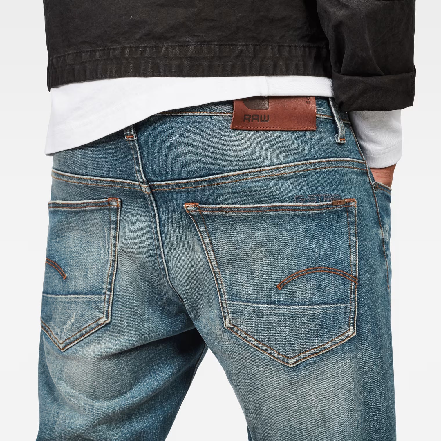 Side view of medium blue straight tapered jeans showcasing distressed details on a white background