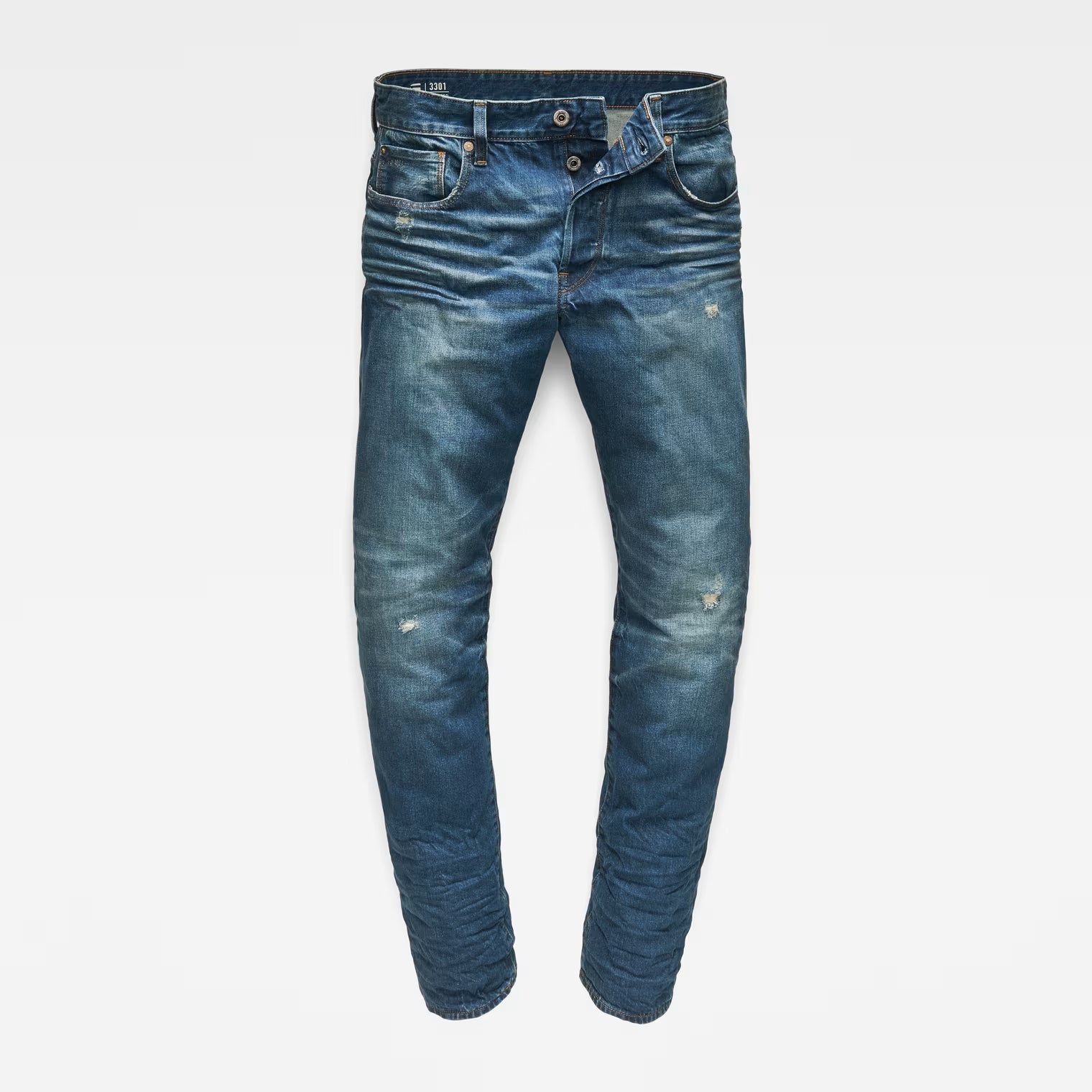 Front view of dark blue tapered jeans with distressed details on a white background.