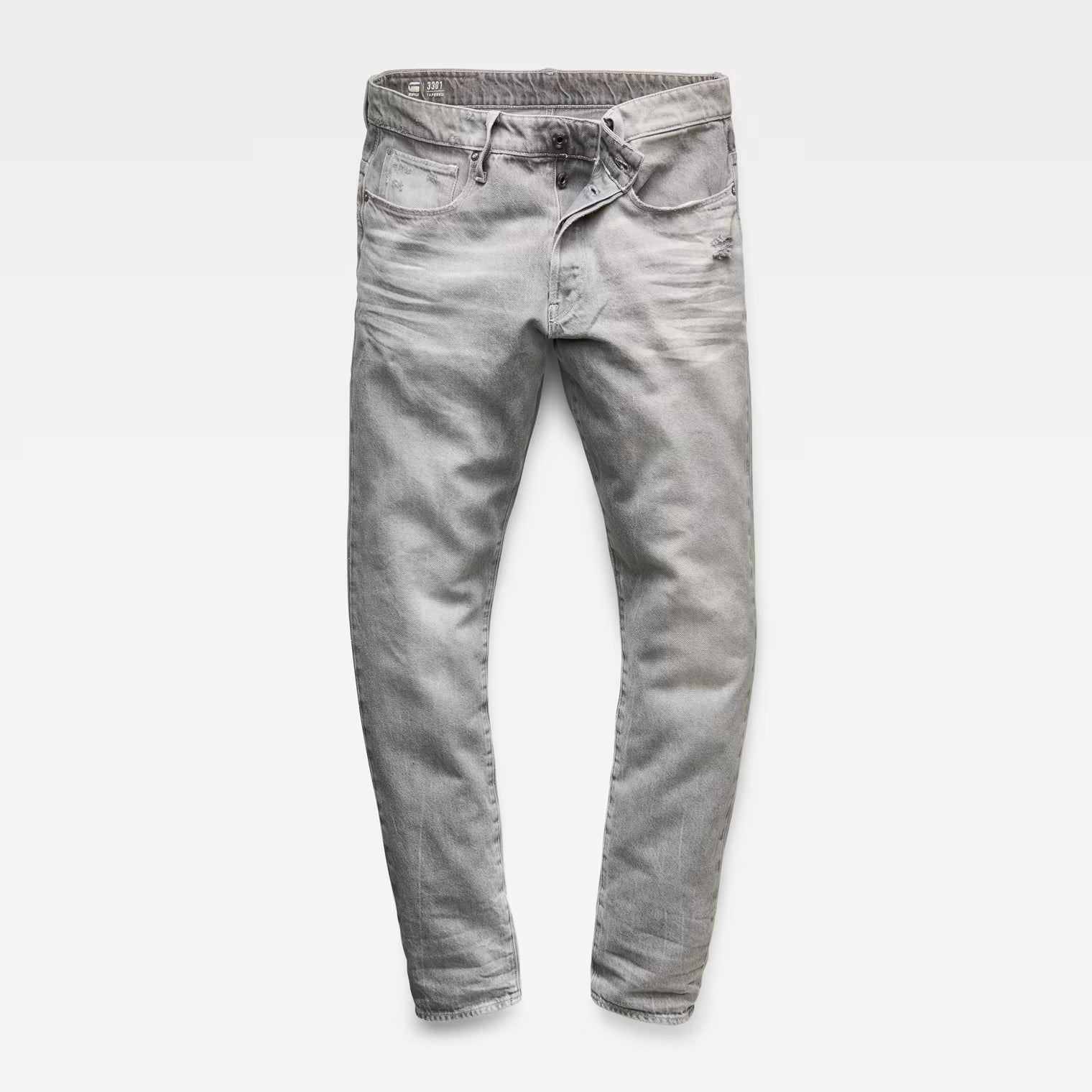 Front view of grey denim pants featuring a tapered fit and five pockets against a white background.