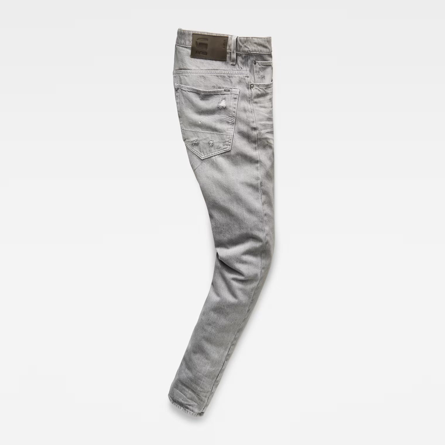 Side view of grey denim pants showcasing the tapered fit on a white background.