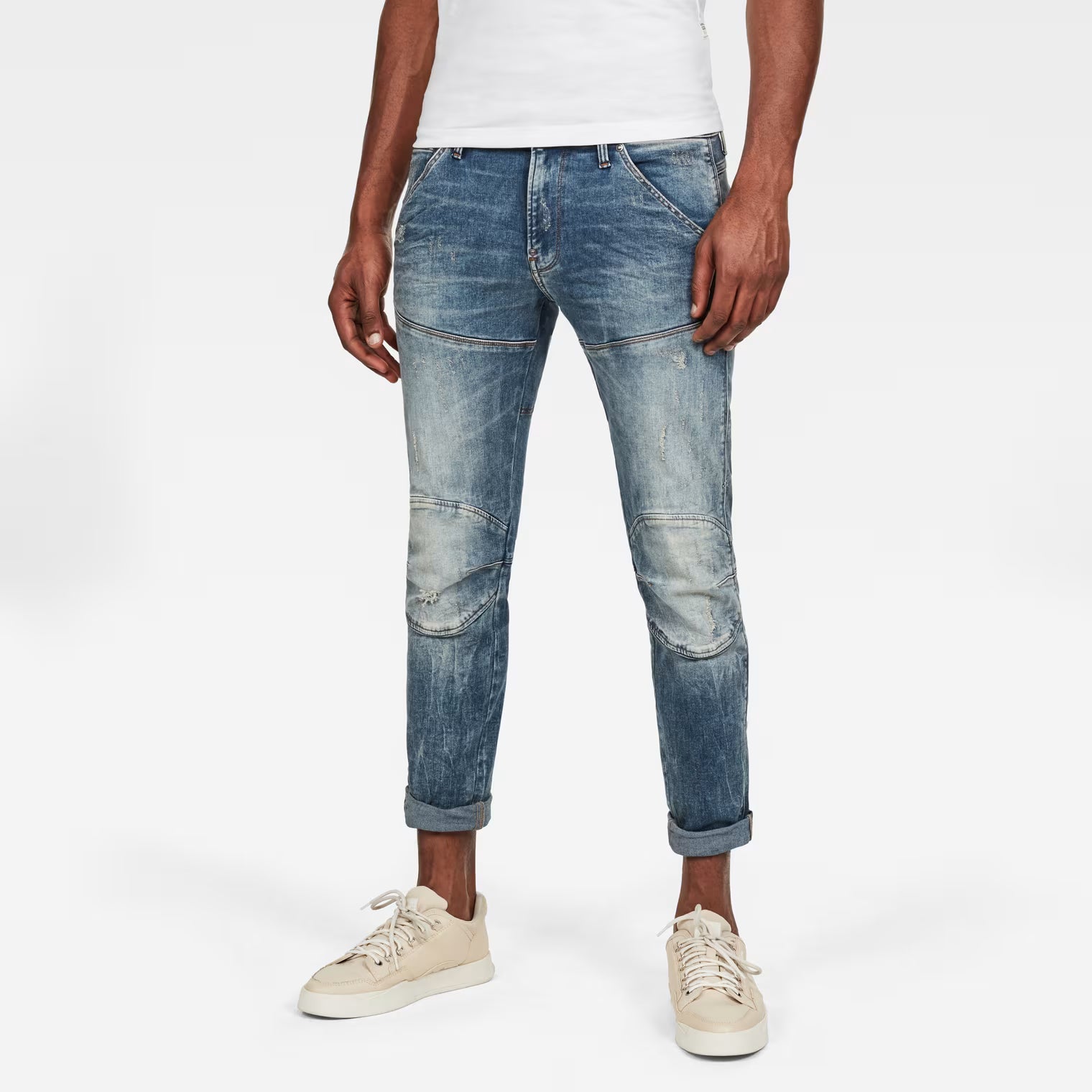 Lifestyle shot of light blue skinny jeans with distressed details on a white background