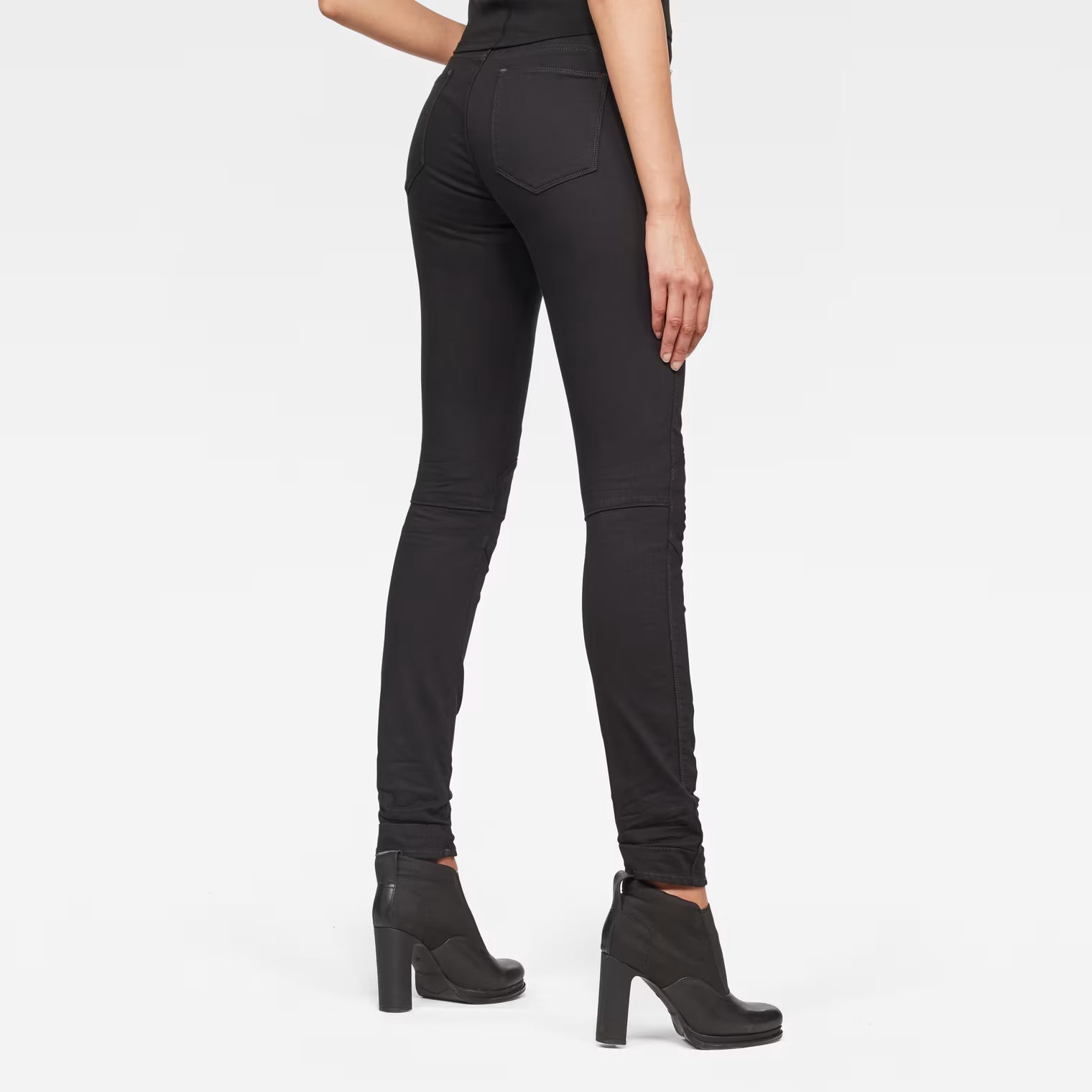Back view of black skinny jeans featuring mid waist and skinny fit on a white background