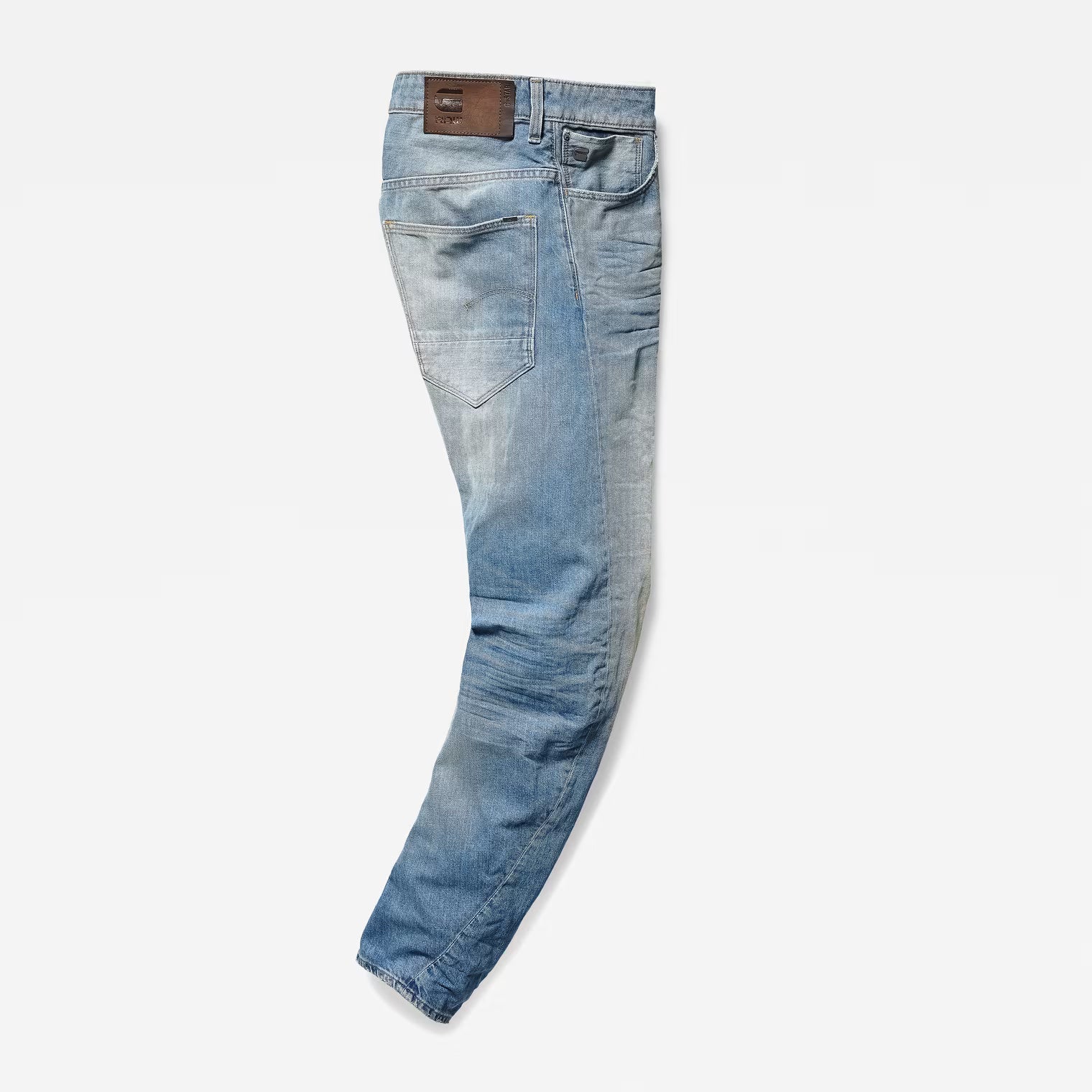 Side view of light blue denim pants showcasing a relaxed fit, tapered leg, and back pocket on a white background.
