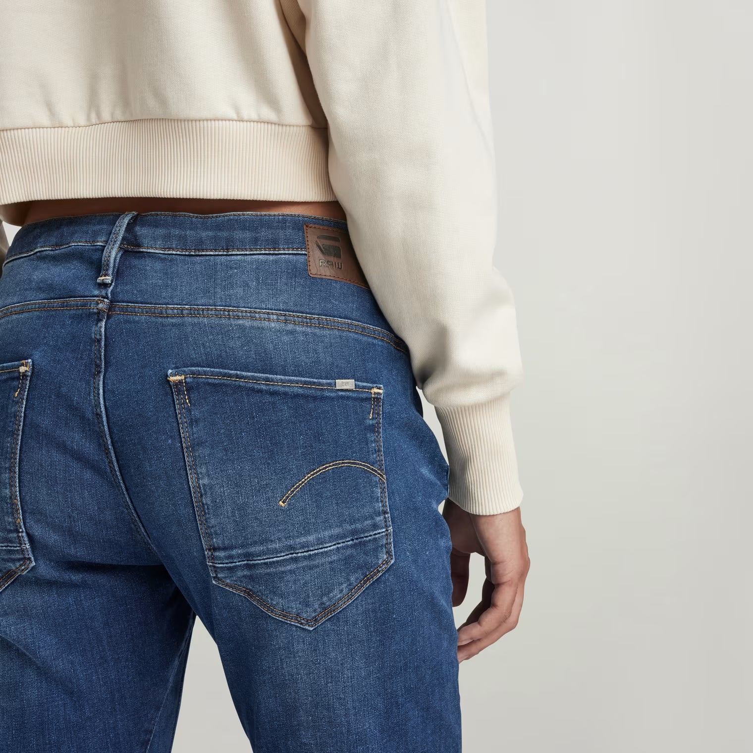 Detail shot of dark blue boyfriend jeans showcasing stitching details from the back view.
