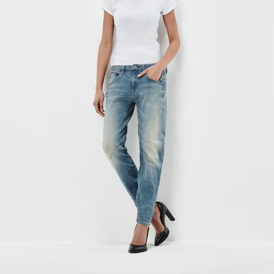 Lifestyle shot of medium blue boyfriend jeans with a low waist and distressed look on a white background.