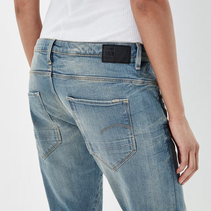 Detail close-up of medium blue boyfriend jeans showing back pockets and label tag on a white background.