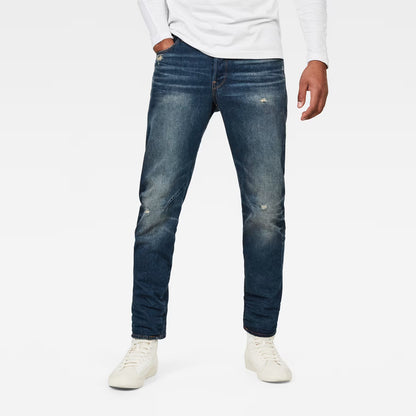 Lifestyle shot of dark blue jeans featuring a relaxed fit and tapered leg on a white background.