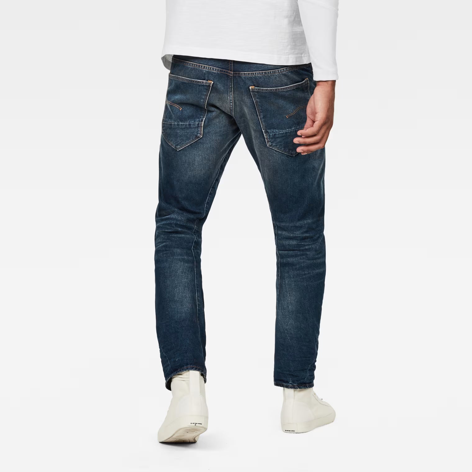 Back view of dark blue jeans showcasing the relaxed fit and tapered leg on a white background.