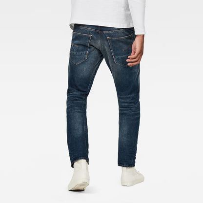 Back view of dark blue jeans showcasing the relaxed fit and tapered leg on a white background.